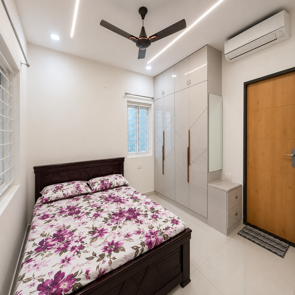 Modern bedroom, luxury bedroom, contemporary bedroom, spacious bedroom, apartment bedroom, stylish bedroom, elegant interior, dark wooden bed, double bed, queen size bed, wooden headboard, floral bedsheet, floral bedding, patterned bedsheet, comfortable mattress, built-in wardrobe, white wardrobe, glossy wardrobe, modern storage, wardrobe cabinets, dressing area, dressing mirror, wall mirror, dressing table, bedside cabinet, wooden furniture, wooden accents, ceiling fan, air conditioner, large windows, window grill, natural light, LED ceiling lights, recessed lighting, modern lighting, false ceiling, glossy floor tiles, white flooring, clean bedroom, minimalist design, neat interior, premium apartment, luxury apartment, residential interior, modern home decor, contemporary furniture, organized bedroom, spacious living space, urban apartment, modern architecture, luxury real estate.